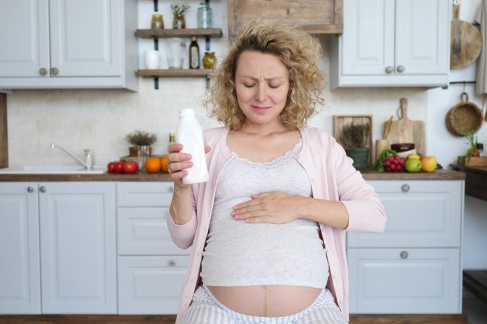 Mujer embarazada bebiendo agua con cara de malestar