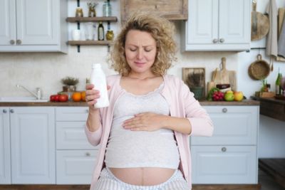 Mujer embarazada bebiendo agua con cara de malestar