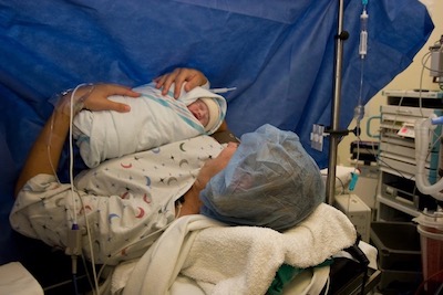 Madre en quirófano con bebé recién nacido en brazos