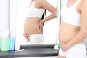 Mujer embarazada mirando su barriga en el espejo
