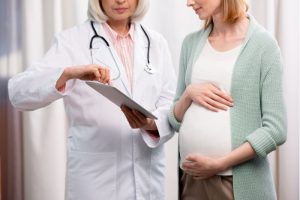 Mujer embarazada junto a médico mirando una tablet