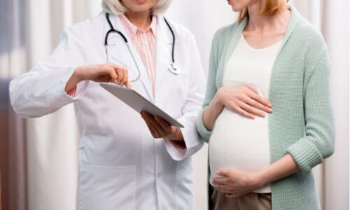 Mujer embarazada junto a médico mirando una tablet
