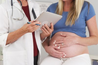 Mujer embarazada tocándose la barriga junto a su médico
