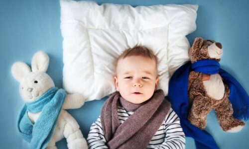 Bebé tumbado con unos peluches con bufanda