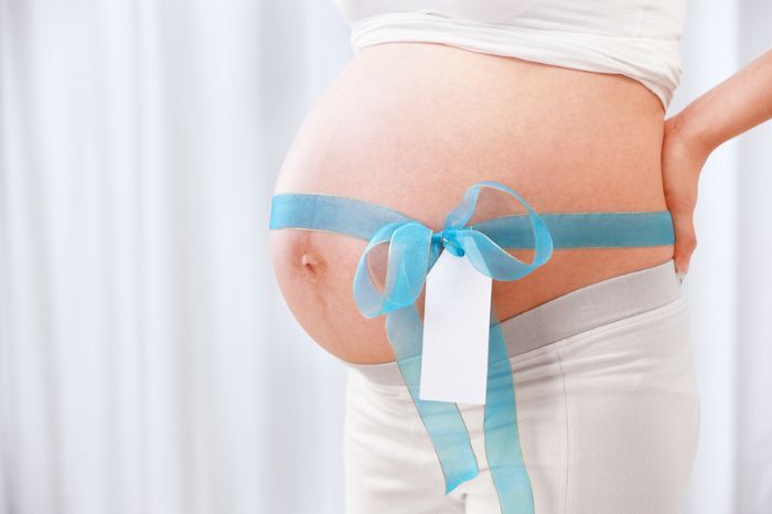 Mujer embarazada con lazo azul en la barriga